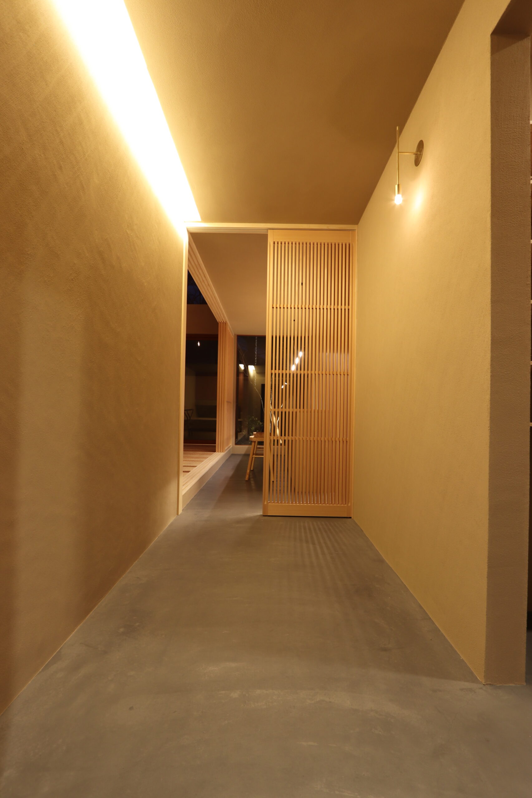 格子越し正面に植木が見える玄関（夜）